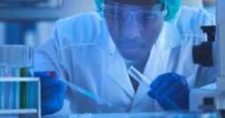 A close-up of a young man in a laboratory wearing protective gear and holding scientific instruments for an experiment.