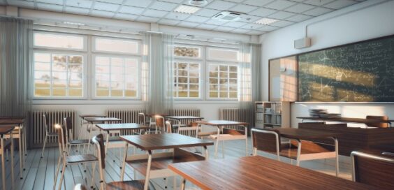 An interior of a classroom with windows on one side of the room and desks throughout facing a blackboard.