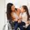 A mother in a wheelchair holding her daughter in her lap and speaking to her. They are in a white room with shelves.