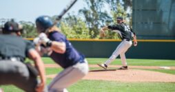 A baseball batter is on the plate while a pitcher is winding up to throw a ball at the hitter.