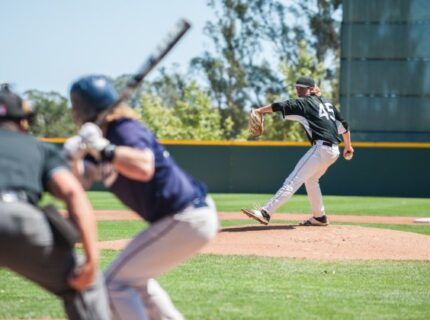 A baseball batter is on the plate while a pitcher is winding up to throw a ball at the hitter.