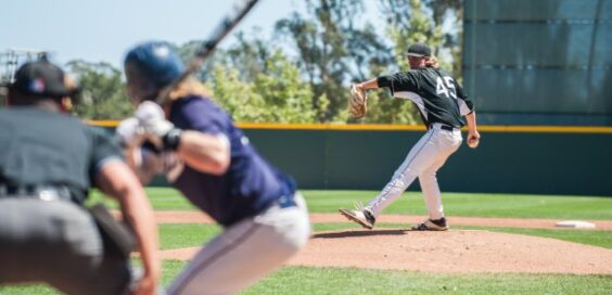 A baseball batter is on the plate while a pitcher is winding up to throw a ball at the hitter.