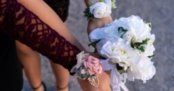 Close-up of white rose bouquet and floral wrist corsages, including white, pink, and burgundy flower accents.
