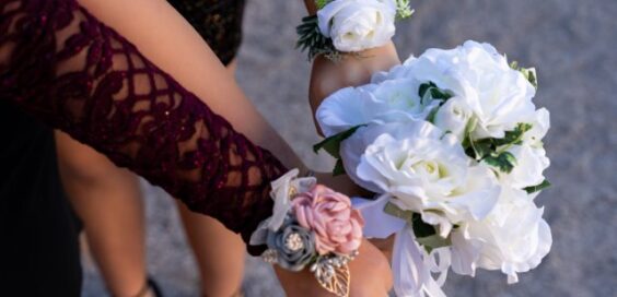 Close-up of white rose bouquet and floral wrist corsages, including white, pink, and burgundy flower accents.