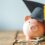 A piggy bank wearing a graduation cap surrounded by cash and coins.